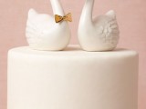 an elegant neutral wedding cake with a ribbon and tiny neutral sugar blooms plus a pair of doves, one of them wearing a bow tie is a beautiful idea