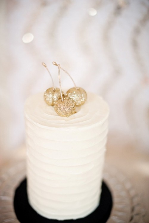 a white buttercream wedding cake topped with gold glitter cherries looks delicious and very cool, any simple wedding cake can be spruced up like that