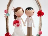 a lovely and pretty kokeshi doll cake topper with a wedding arch over them is a stylish idea for a bold and fun wedding
