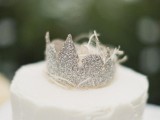 a white buttercream wedding cake topped with a silver glitter crown is a lovely idea for a wedding with a royal feel