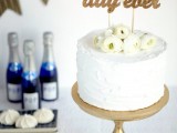 a white buttercream wedding cake topped with some fresh white ranunculus and with a godl calligraphy cake topper is a great idea for a chic neutral wedding