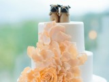 a white wedding cake decorated with a large orange sugar bloom and topped with two little dog cake toppers for a dog-lover wedding