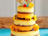 a naked wedding cake decorated with fresh bright blooms and funny edible bird and lion cake toppers that symbolize the couple