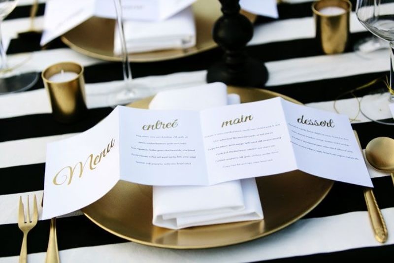 A folded menu with gold calligraphy is a stylish modern idea for a chic wedding