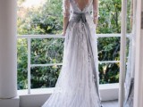 a romantic lace applique A-line wedding dress with a low back, long sleeves, a grey sash and a train for a dreamy bridal look