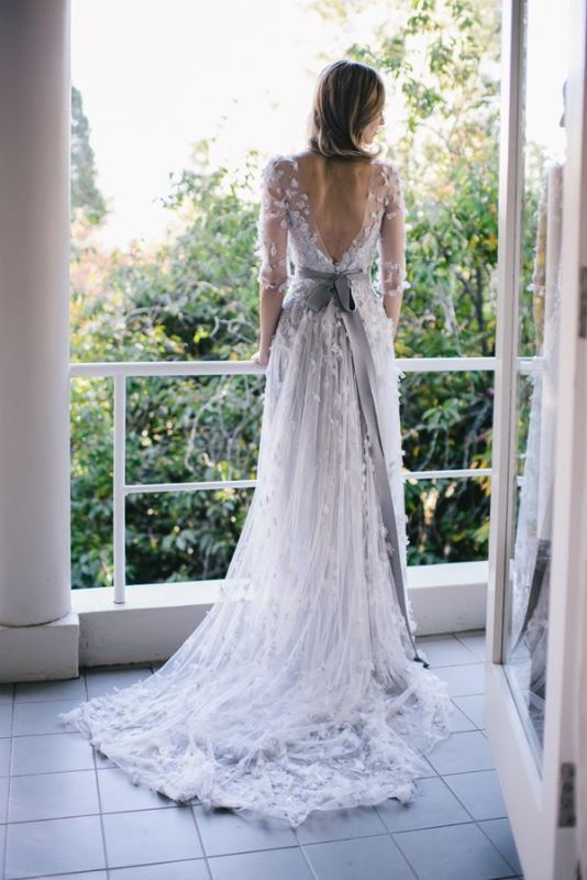 A romantic lace applique A line wedding dress with a low back, long sleeves, a grey sash and a train for a dreamy bridal look