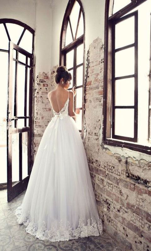 a beautiful A-line wedding dress with a lace bodice on spaghetti straps, a layered skirt with a tulle edge plus a refined top knot for a gorgeous look