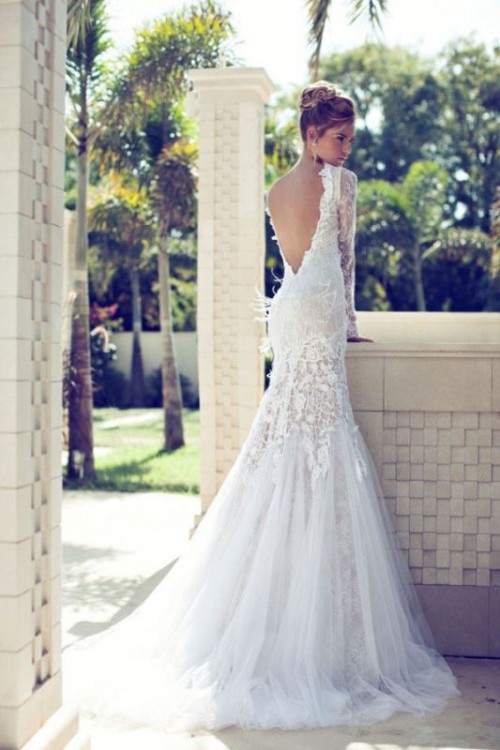 a refined mermaid wedding dress of lace and with lace appliques, with a low back, long sleeves and a tulle skirt with a train