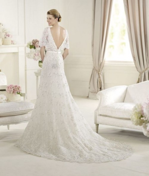 a lace embellished A-line wedding dress with a low back and short sleeves and a train is very formal and very chic