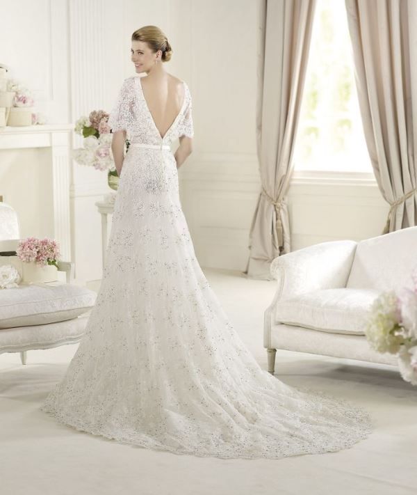 A lace embellished A line wedding dress with a low back and short sleeves and a train is very formal and very chic