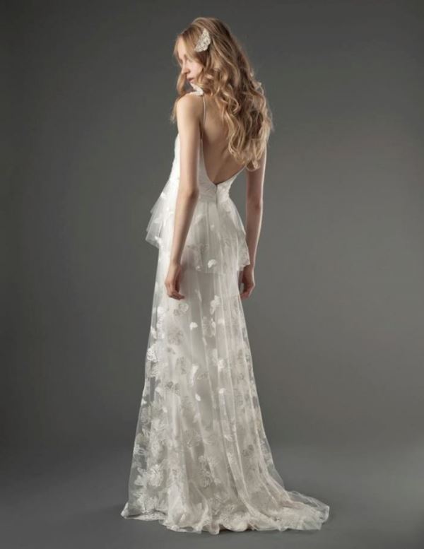 A lace A line wedding dress with a tiered skirt and a train, a low back and spaghetti straps is very girlish
