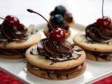mini cookie sandwiches with chocolate, chocolate icing, cherries and almond petals on top are fantastic and decadent