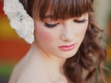 a long wavy half updo with a braid on top and a full fringe bang plus a large bloom on the other side