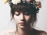 a wavy updo with long wavy bangs and a colorful floral crown with baby’s breath