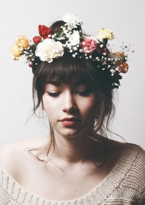 a wavy updo with long wavy bangs and a colorful floral crown with baby's breath
