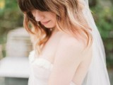 a medium length hairstyle with loose waves down, a braid on top and bangs plus a long veil