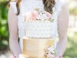 a lovely wedding cake with a polka dot and a gold tier and white and pink blooms and greenery on top is a gorgeous idea for a spring or summer wedding