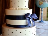 a white wedding cake with polka dot and striped tiers, a navy ribbon bow is a lovely idea for a chic wedding cake with touches of navy