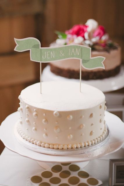 a white one-tier polka dot wedding cake topped with a green cake topper is a stylish and chic idea for a modern wedding