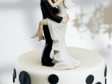 a white wedding cake with black polka dots and funny couple cake toppers is a gorgeous idea for a wedding