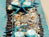 a bamboo runner, seashells and pebbles, starfish plus turquoise candles in candle holders