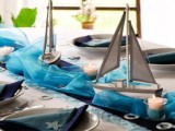 a blue table runner and boats plus candles for a beach or coastal wedding centerpiece