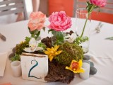 a tropical beach wedding centerpiece with driftwood, tropical blooms, a table number and candles