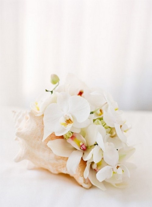 a large seashell with white orchids is a very creative tropical beach wedding centerpiece