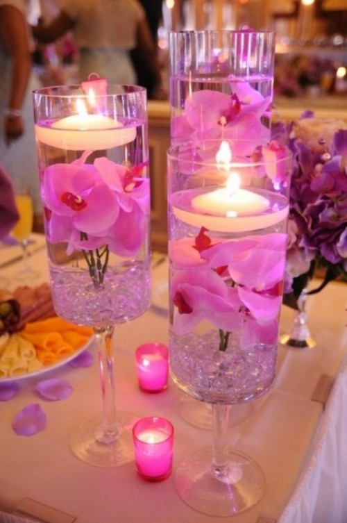 glasses with bright purple petals and floating candles and candles around for a tropical beach wedding