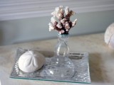 a silver tray with a starfish print, a vase with a piece of coral is a simple and casual idea