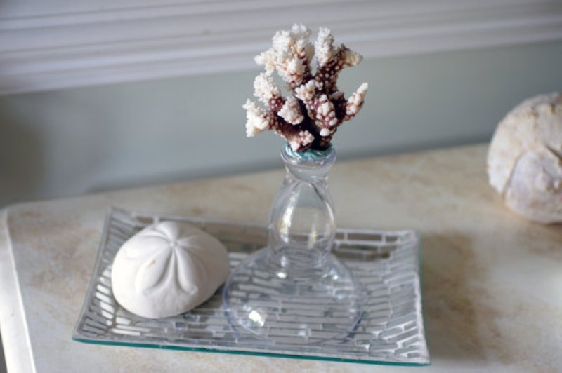 A silver tray with a starfish print, a vase with a piece of coral is a simple and casual idea
