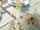 neutral blooms in a blue vase and air plants is a relaxed and chic idea of a wedding centerpiece