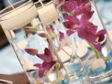 a mirror with tall glasses and purple orchids plus floating candles is a proper idea for a tropical beach wedding