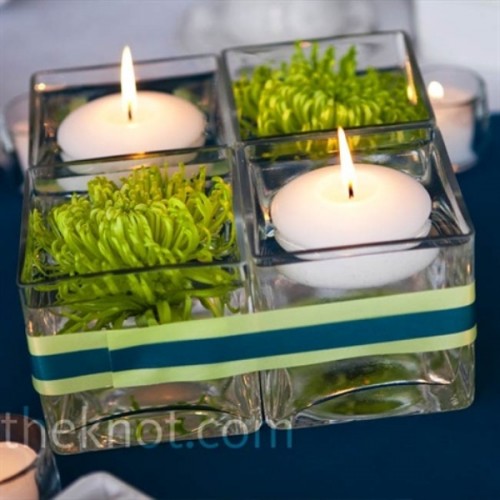 a glass container wth floating candles and green blooms plus a striped ribbon to highlight it