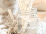 a jar with sand, dried grasses and driftwood is a simple beach centerpiece idea