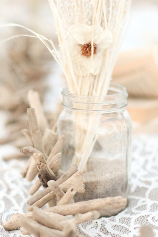 A jar with sand, dried grasses and driftwood is a simple beach centerpiece idea