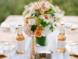 a peachy, white and green floral wedding centerpiece plus a pallet sign with a seashell
