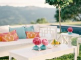 a cool and simple outdoor wedding lounge with white vintage furniture, bright pillows and blooms is a lovely idea for a spring or summer wedding