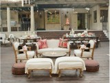 a refined vintage outdoor wedding lounge with white upholstery and bright pillows, low poufs and a round metal table