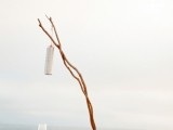 a neutral beach lounge with pillows, driftwood, candle lanterns and blankets is a great idea for a beach wedding