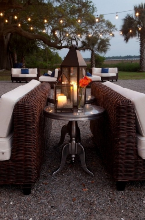 an outdoor wedding lounge with wicker furniture, white upholstery, coffee tables and lanterns is a lovely space to enjoy