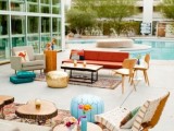 a mid-century boho colorful outdoor lounge with rich-stained furniture, neutral and bright upholstery and colorful pillows, rugs and poufs