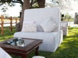 a refined outdoor wedding lounge with printed sofas, dark-stained coffee tables, curtains over the chairs