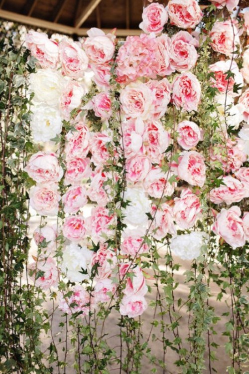 a fantastic wedding backdrop made of fresh foliage and pink paper peonies that look natural and perfectly imitate fresh blooms and greenery