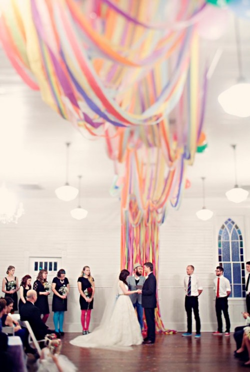 a colorful ribbon wedding backdrop that goes up to the ceiling and creates an installation there is a unique idea