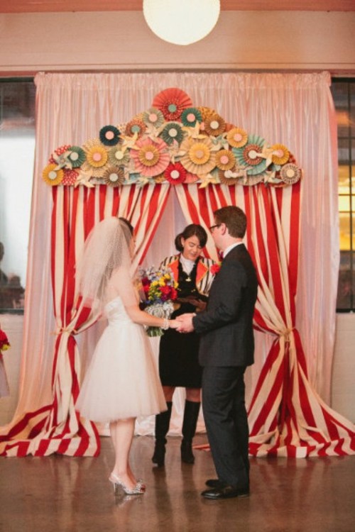 a colorful retro wedding backdrop imitating a tent, with striped curtains and colorful paper fans is a bright and fun idea