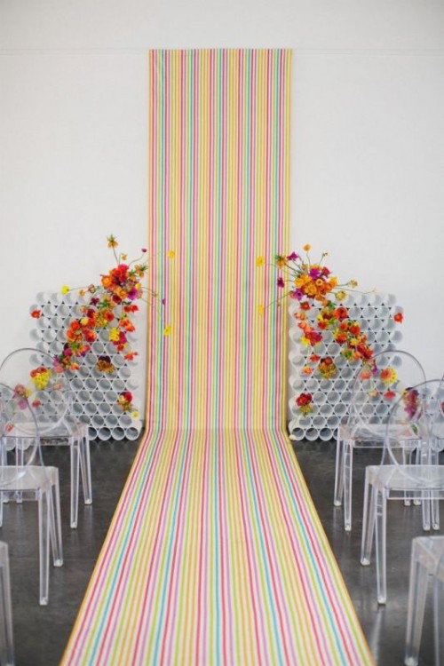 a chic and bright wedding backdrop of colorul striped wallpaper and PVC pipe installations with some colorful blooms is a bold idea