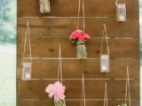 a rustic wedding backdrop with candle lanterns and bright floral arrangements in jars is a cool and cozy idea