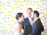 a bright modern wedding backdrop made of yellow and grey large polka dots attached right to the wall – simple and cute