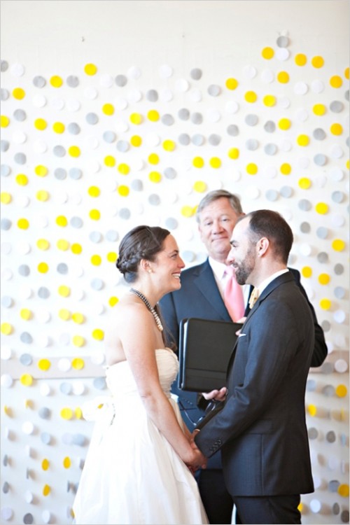 a bright modern wedding backdrop made of yellow and grey large polka dots attached right to the wall - simple and cute